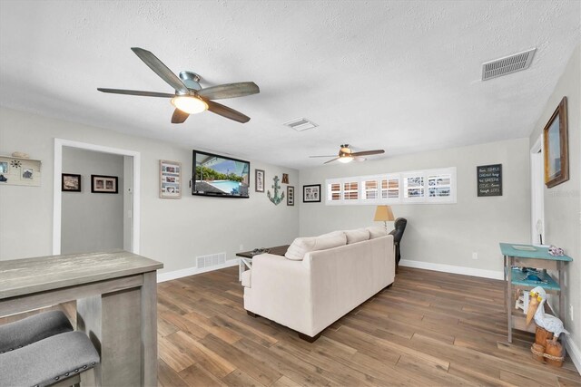 9591 Commodore Dr, Seminole, FL 33776 - living area with a ceiling fan, a textured ceiling, dark wood-style flooring, and baseboards