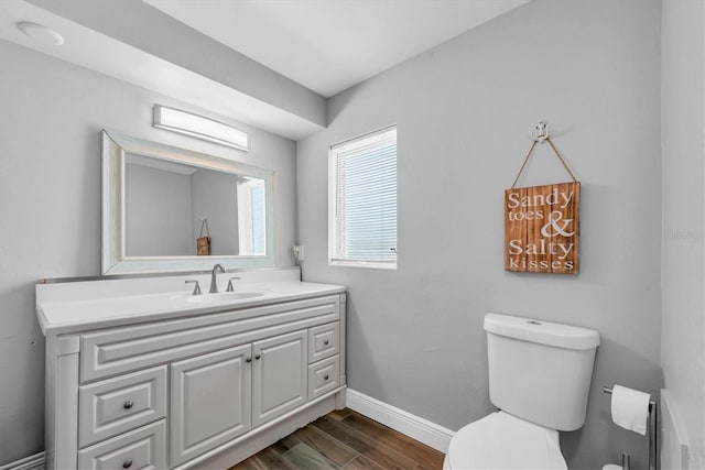 9591 Commodore Dr, Seminole, FL 33776 - half bathroom featuring toilet, vanity, wood finished floors, and baseboards