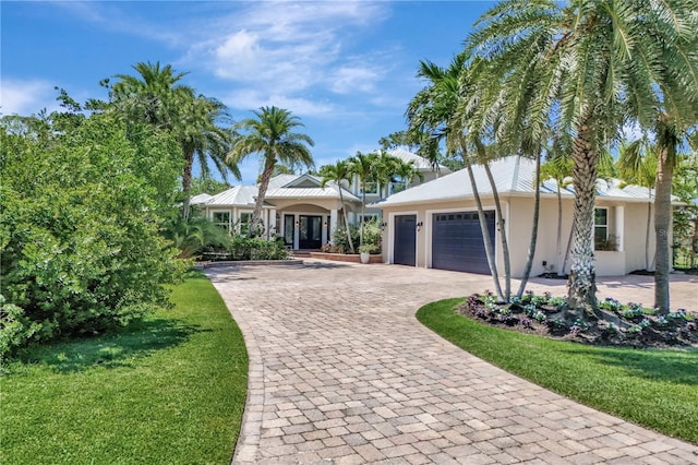 1817 Piccadilly Cir, Cape Coral, FL 33991 - view of front of home featuring stucco siding, decorative driveway, a garage, a front yard, and a standing seam roof