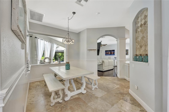 1817 Piccadilly Cir, Cape Coral, FL 33991 - dining room featuring arched walkways, a wainscoted wall, decorative columns, a chandelier, and light stone finish flooring