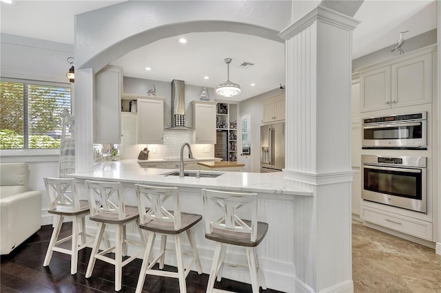 1817 Piccadilly Cir, Cape Coral, FL 33991 - kitchen with wall chimney range hood, stainless steel appliances, a sink, open shelves, and a peninsula
