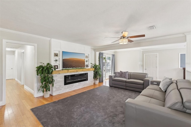 3966 High Bluff Dr, Largo, FL 33770 - living area with a ceiling fan, light wood-type flooring, crown molding, a glass covered fireplace, and baseboards