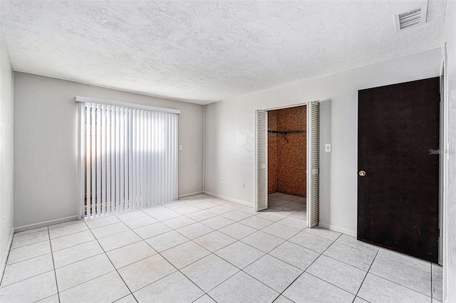 4309 Cedar Grove St, Holiday, FL 34691 - unfurnished bedroom featuring a closet, light tile patterned floors, baseboards, and a textured ceiling