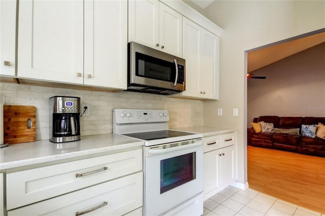 11641 Branch Mooring Dr, Tampa, FL 33635 - kitchen with white range with electric stovetop, stainless steel microwave, decorative backsplash, light countertops, and white cabinets