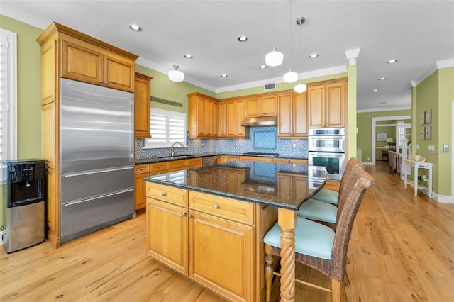 13303 Gulf Ln, Madeira Beach, FL 33708 - kitchen with stainless steel appliances, under cabinet range hood, ornamental molding, tasteful backsplash, and a center island