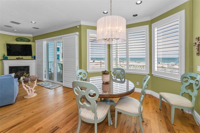 13303 Gulf Ln, Madeira Beach, FL 33708 - dining room with ornamental molding, wood finished floors, a fireplace, a chandelier, and baseboards