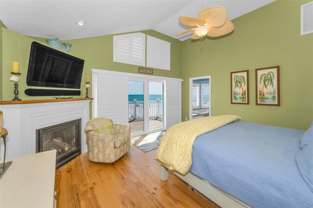 13303 Gulf Ln, Madeira Beach, FL 33708 - bedroom with access to outside, wood finished floors, a glass covered fireplace, a ceiling fan, and high vaulted ceiling