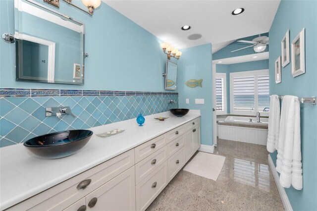 13303 Gulf Ln, Madeira Beach, FL 33708 - full bathroom with double vanity, a garden tub, a wainscoted wall, a ceiling fan, and tile walls