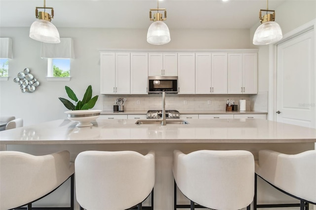 10036 Beachwalk Dr, Englewood, FL 34223 - kitchen with stainless steel microwave, tasteful backsplash, a sink, and white cabinetry