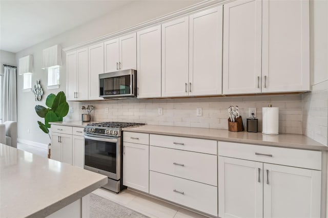 10036 Beachwalk Dr, Englewood, FL 34223 - kitchen with appliances with stainless steel finishes, decorative backsplash, light countertops, and white cabinetry
