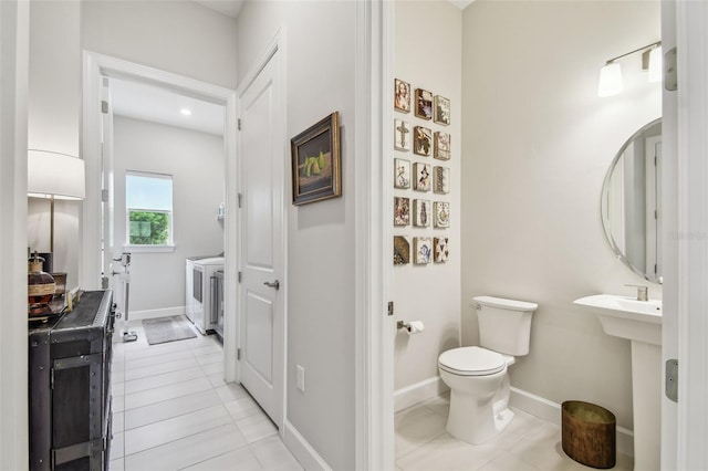 10036 Beachwalk Dr, Englewood, FL 34223 - bathroom with washer and clothes dryer, toilet, tile patterned floors, and baseboards