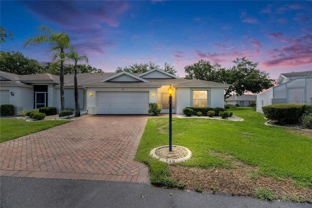 746 Masterpiece Dr, Sun City Center, FL 33573 - ranch-style house featuring decorative driveway, a garage, stucco siding, a yard, and a shingled roof