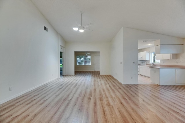 746 Masterpiece Dr, Sun City Center, FL 33573 - unfurnished living room with lofted ceiling, a ceiling fan, light wood-style flooring, baseboards, and a sink