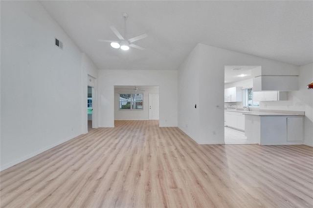 746 Masterpiece Dr, Sun City Center, FL 33573 - unfurnished living room with lofted ceiling, ceiling fan, and light wood-style flooring