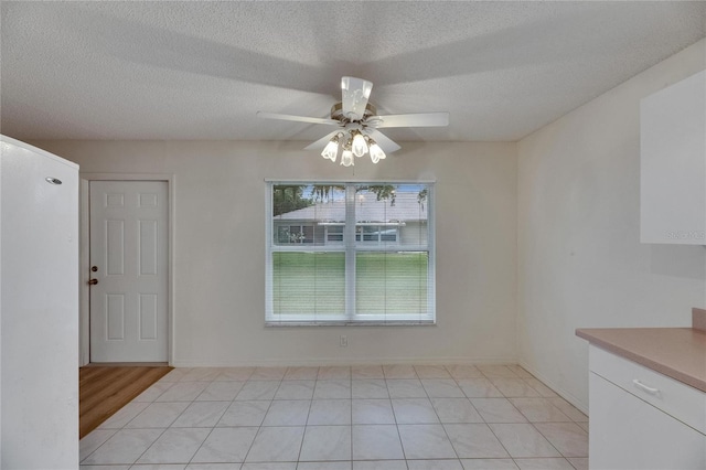 746 Masterpiece Dr, Sun City Center, FL 33573 - unfurnished dining area with ceiling fan, a textured ceiling, and light tile patterned floors