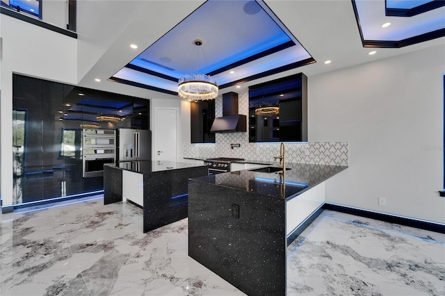 6520 Simone Shores Cir, Apollo Beach, FL 33572 - kitchen with wall chimney exhaust hood, high quality appliances, a raised ceiling, a sink, and dark cabinetry