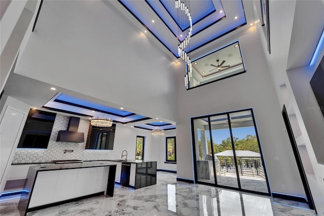 6520 Simone Shores Cir, Apollo Beach, FL 33572 - kitchen featuring modern cabinets, a raised ceiling, a kitchen island, light marble finish floors, and a towering ceiling