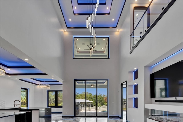 6520 Simone Shores Cir, Apollo Beach, FL 33572 - unfurnished living room featuring a high ceiling, a sink, a tray ceiling, a chandelier, and recessed lighting