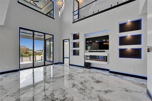 6520 Simone Shores Cir, Apollo Beach, FL 33572 - unfurnished living room with marble tiled floors, baseboards, a high ceiling, and a glass covered fireplace