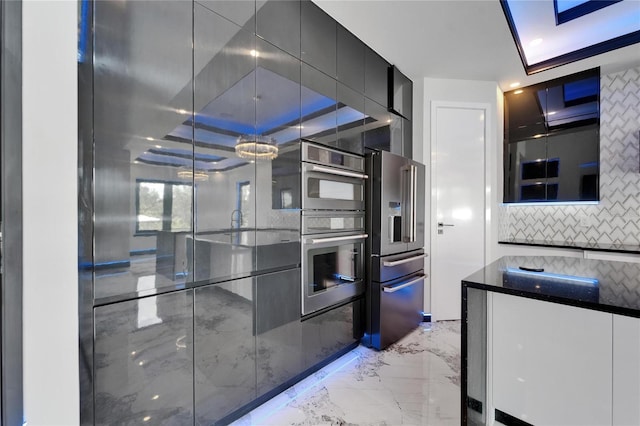 6520 Simone Shores Cir, Apollo Beach, FL 33572 - kitchen with appliances with stainless steel finishes, light marble finish flooring, decorative backsplash, modern cabinets, and dark countertops