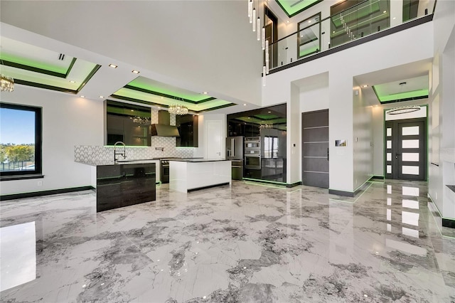 6526 Simone Shores Cir, Apollo Beach, FL 33572 - kitchen featuring wall chimney range hood, a kitchen island, a chandelier, and a raised ceiling
