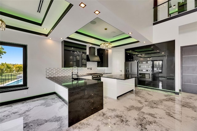 6526 Simone Shores Cir, Apollo Beach, FL 33572 - kitchen featuring a sink, a tray ceiling, wall chimney range hood, and light marble finish floors