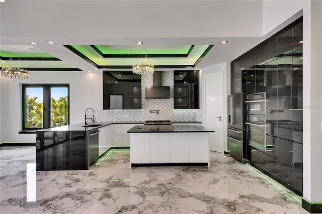 6526 Simone Shores Cir, Apollo Beach, FL 33572 - kitchen featuring a chandelier, modern cabinets, a raised ceiling, wall chimney exhaust hood, and backsplash