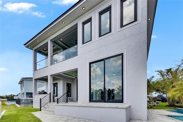 6526 Simone Shores Cir, Apollo Beach, FL 33572 - view of side of home featuring stucco siding, a patio, a balcony, and a yard