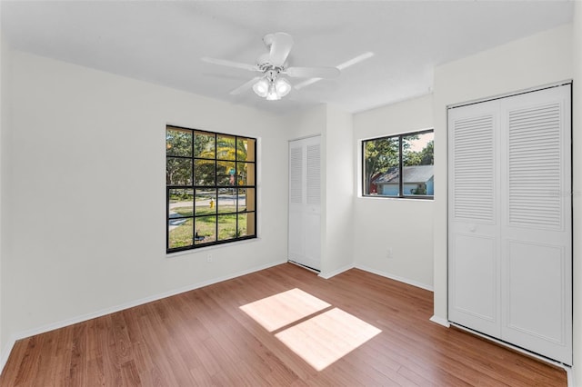 3041 Oak View Dr, Palm Harbor, FL 34684 - unfurnished bedroom with wood finished floors, multiple closets, and ceiling fan