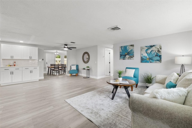 6804 Tierra Verde St, Port Richey, FL 34668 - living area featuring baseboards, light wood-style floors, ceiling fan, and a textured ceiling