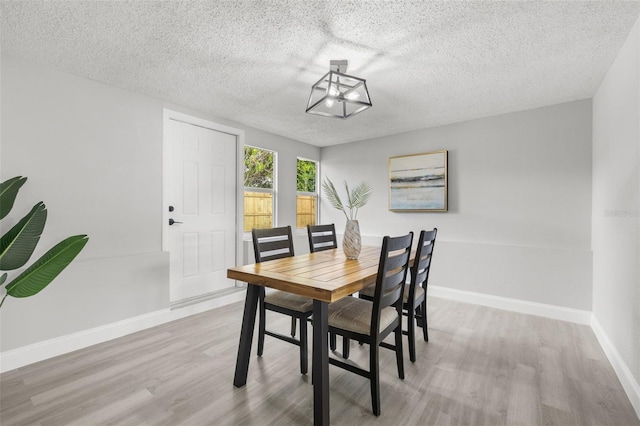 6804 Tierra Verde St, Port Richey, FL 34668 - dining area featuring wood finished floors, a textured ceiling, baseboards, and a chandelier