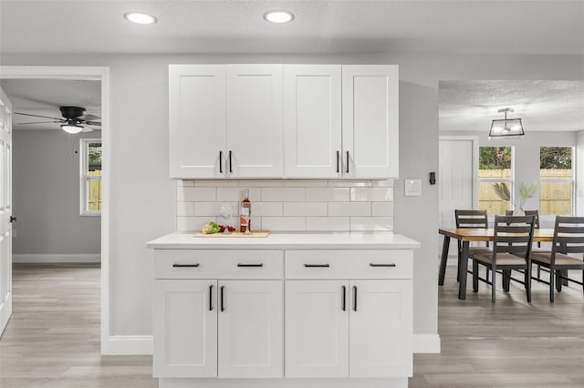 6804 Tierra Verde St, Port Richey, FL 34668 - bar featuring baseboards, backsplash, light wood-type flooring, ceiling fan, and a textured ceiling