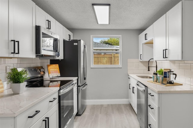 6804 Tierra Verde St, Port Richey, FL 34668 - kitchen featuring appliances with stainless steel finishes, a sink, light wood-style flooring, a textured ceiling, and light stone countertops