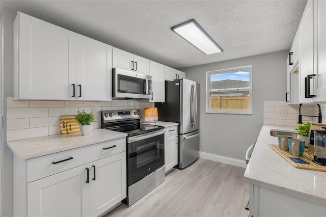 6804 Tierra Verde St, Port Richey, FL 34668 - kitchen with appliances with stainless steel finishes, light wood-style flooring, a sink, baseboards, and tasteful backsplash