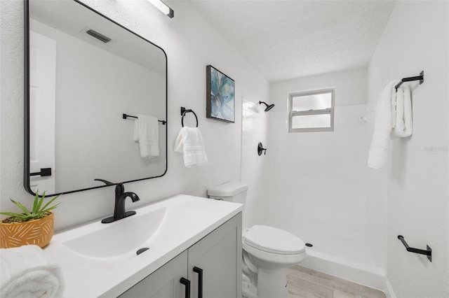 6804 Tierra Verde St, Port Richey, FL 34668 - bathroom featuring toilet, tiled shower, vanity, and a textured ceiling