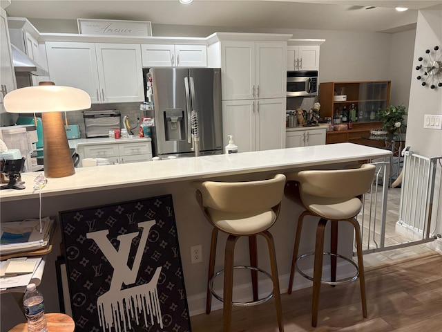 20938 Sunsweet Ct, Land O Lakes, FL 34637 - kitchen with stainless steel appliances, light countertops, white cabinetry, a breakfast bar, and backsplash
