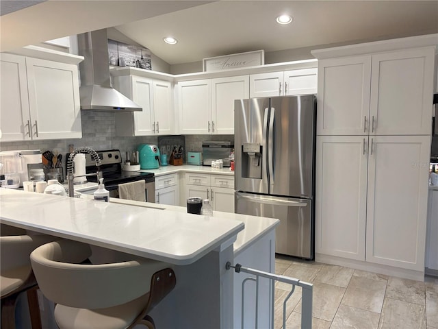 20938 Sunsweet Ct, Land O Lakes, FL 34637 - kitchen featuring appliances with stainless steel finishes, wall chimney exhaust hood, a peninsula, backsplash, and light countertops