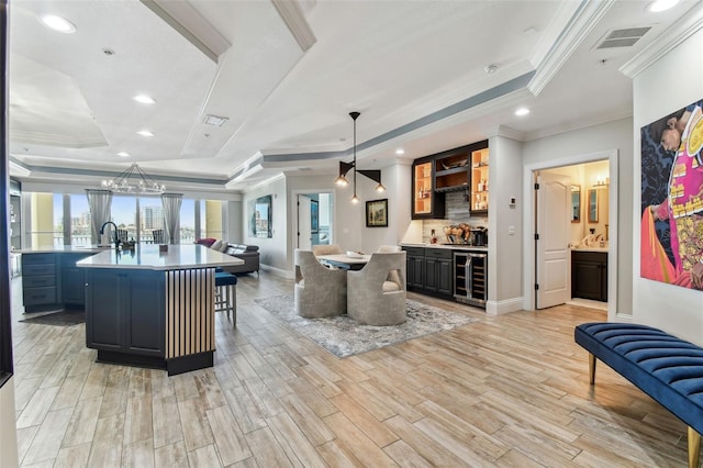 200 Skiff Pt Unit 202, Clearwater Beach, FL 33767 - kitchen with beverage cooler, a tray ceiling, open floor plan, crown molding, and a spacious island