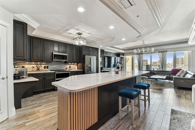 200 Skiff Pt Unit 202, Clearwater Beach, FL 33767 - kitchen featuring stainless steel appliances, a chandelier, a raised ceiling, crown molding, and light wood-style flooring