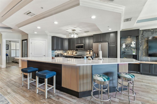 200 Skiff Pt Unit 202, Clearwater Beach, FL 33767 - kitchen with stainless steel appliances, ornamental molding, a raised ceiling, a large island with sink, and backsplash