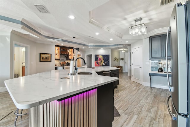 200 Skiff Pt Unit 202, Clearwater Beach, FL 33767 - kitchen featuring freestanding refrigerator, a tray ceiling, a sink, a large island, and crown molding