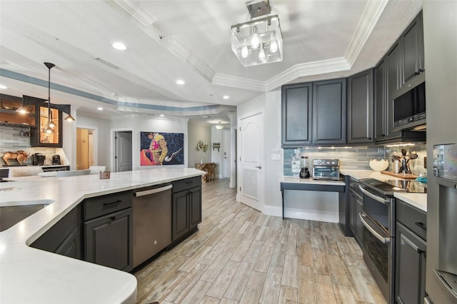 200 Skiff Pt Unit 202, Clearwater Beach, FL 33767 - kitchen with appliances with stainless steel finishes, a raised ceiling, backsplash, light wood-style floors, and crown molding