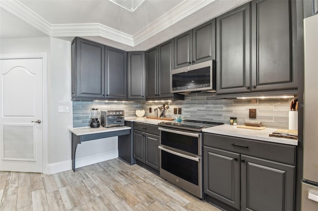 200 Skiff Pt Unit 202, Clearwater Beach, FL 33767 - kitchen featuring appliances with stainless steel finishes, gray cabinets, light countertops, decorative backsplash, and crown molding