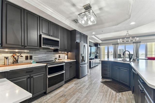 200 Skiff Pt Unit 202, Clearwater Beach, FL 33767 - kitchen featuring stainless steel appliances, a sink, a tray ceiling, light countertops, and tasteful backsplash