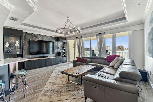 200 Skiff Pt Unit 202, Clearwater Beach, FL 33767 - living room with a tray ceiling, ornamental molding, a chandelier, light wood-style floors, and baseboards