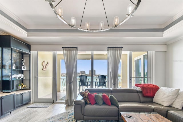 200 Skiff Pt Unit 202, Clearwater Beach, FL 33767 - living area featuring a raised ceiling, ornamental molding, light wood finished floors, and a chandelier