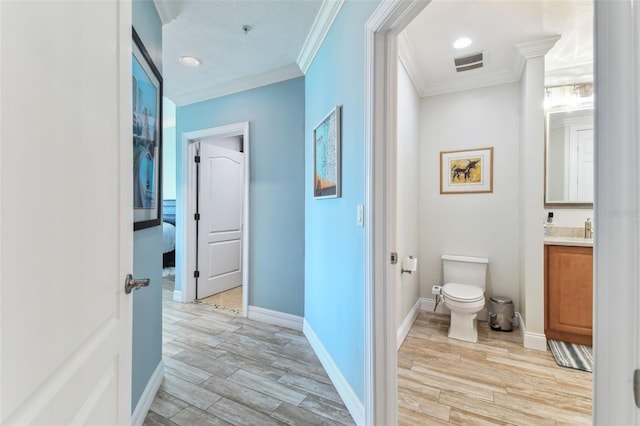 200 Skiff Pt Unit 202, Clearwater Beach, FL 33767 - bathroom with crown molding, vanity, toilet, wood finished floors, and baseboards