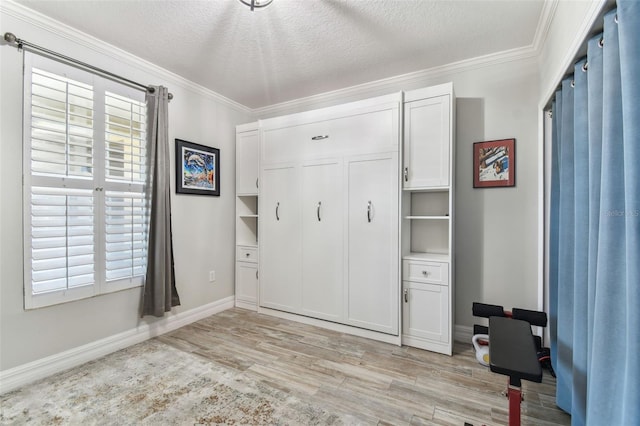 200 Skiff Pt Unit 202, Clearwater Beach, FL 33767 - unfurnished bedroom featuring light wood-style flooring, crown molding, baseboards, a textured ceiling, and multiple windows