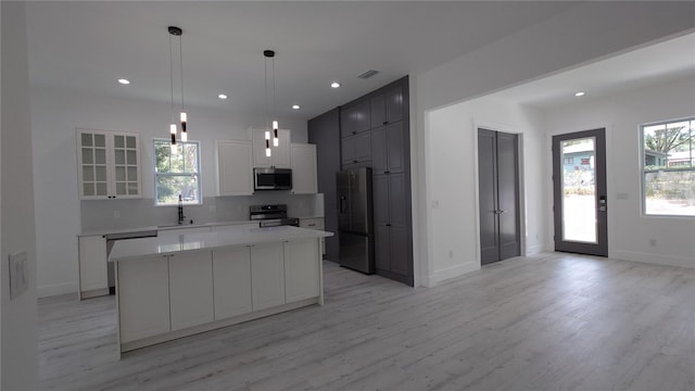 7011 N 15th St, Tampa, FL 33610 - kitchen featuring appliances with stainless steel finishes, light wood finished floors, tasteful backsplash, a center island, and a sink