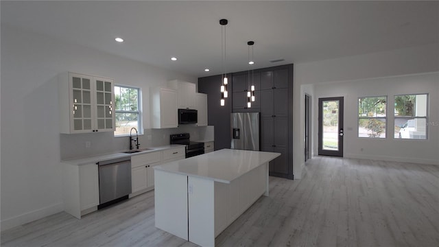 7011 N 15th St, Tampa, FL 33610 - kitchen with black appliances, a sink, light wood finished floors, a center island, and glass insert cabinets
